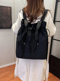 Person wearing a black drawstring backpack indoors.