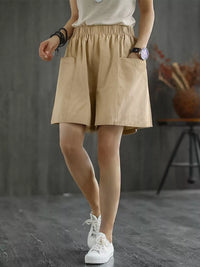 Person wearing a beige skirt with white sneakers on a gray background