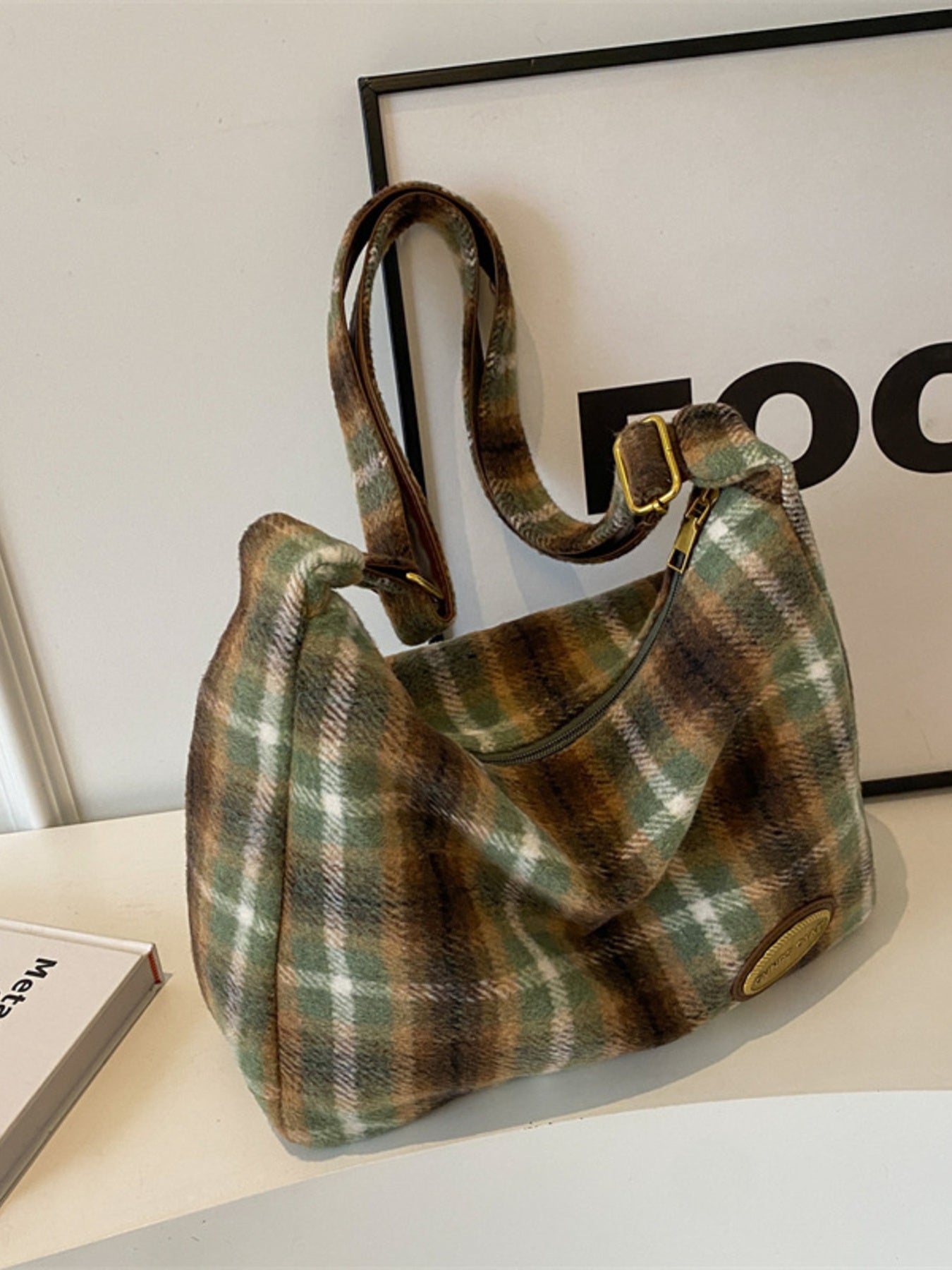 Plaid patterned handbag on a light surface with a blurred background