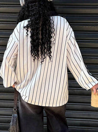 Person wearing a white and black striped shirt with a blurred background