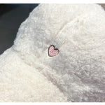 Close-up of a fluffy white surface with a pink heart embroidered on it.