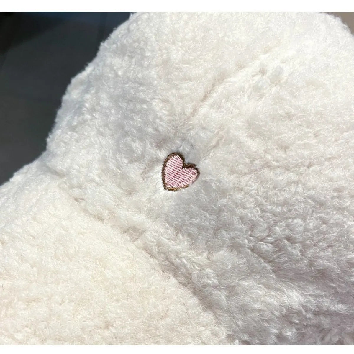 Close-up of a fluffy white surface with a pink heart embroidered on it.