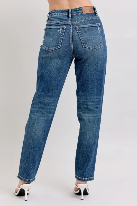 Blue jeans worn by a person on a plain background