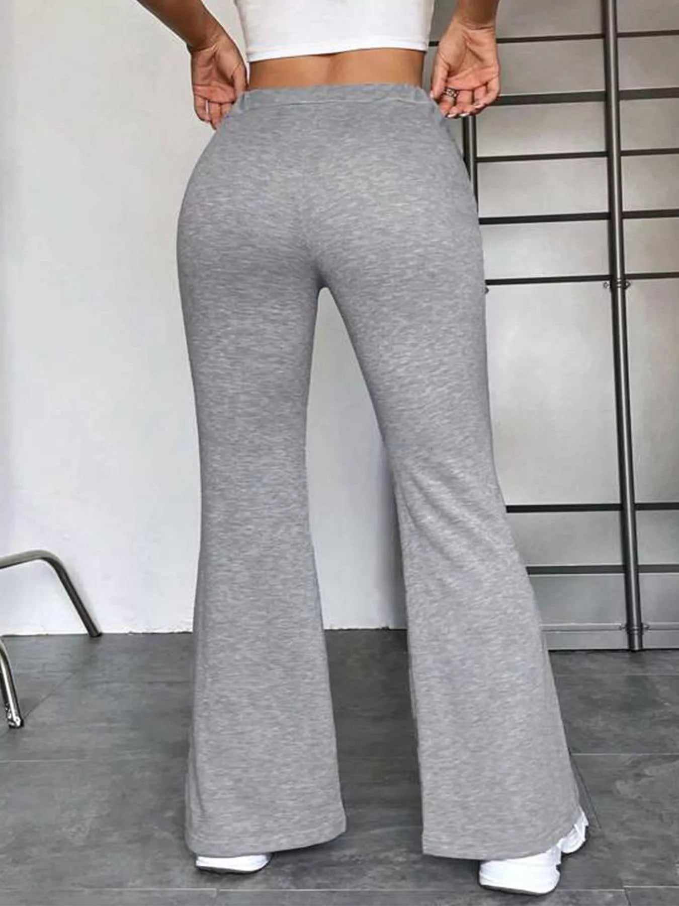 Person wearing gray flared pants in a minimal indoor setting