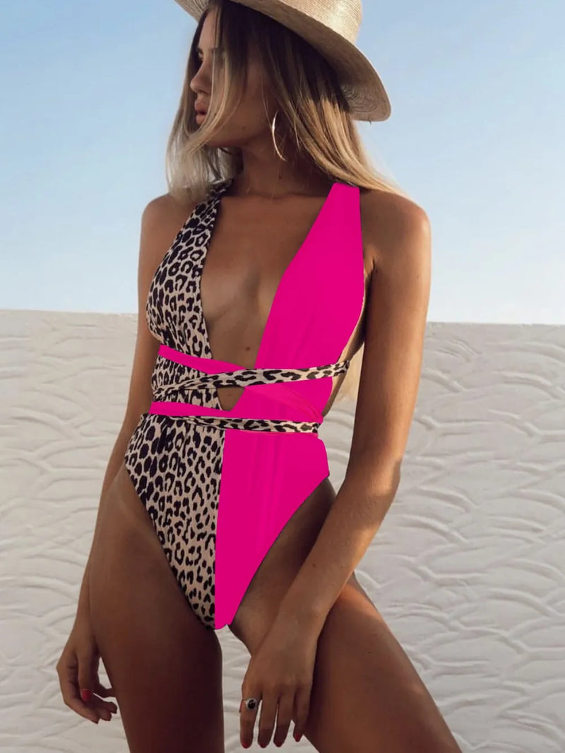 Woman wearing a pink and leopard print swimsuit on a beach.