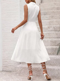 Woman wearing a white sleeveless dress standing on stone steps.