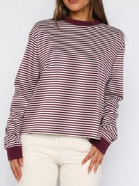 Person wearing a striped sweater with a plain background