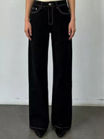 Person wearing black flared jeans against a plain background