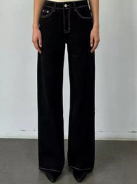 Person wearing black flared jeans against a plain background