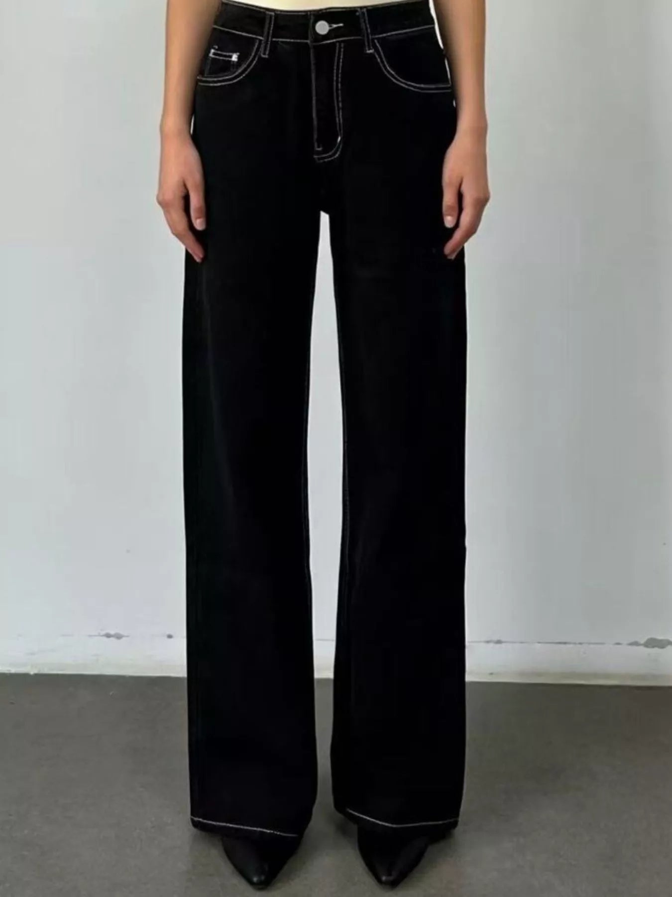 Person wearing black flared jeans against a plain background