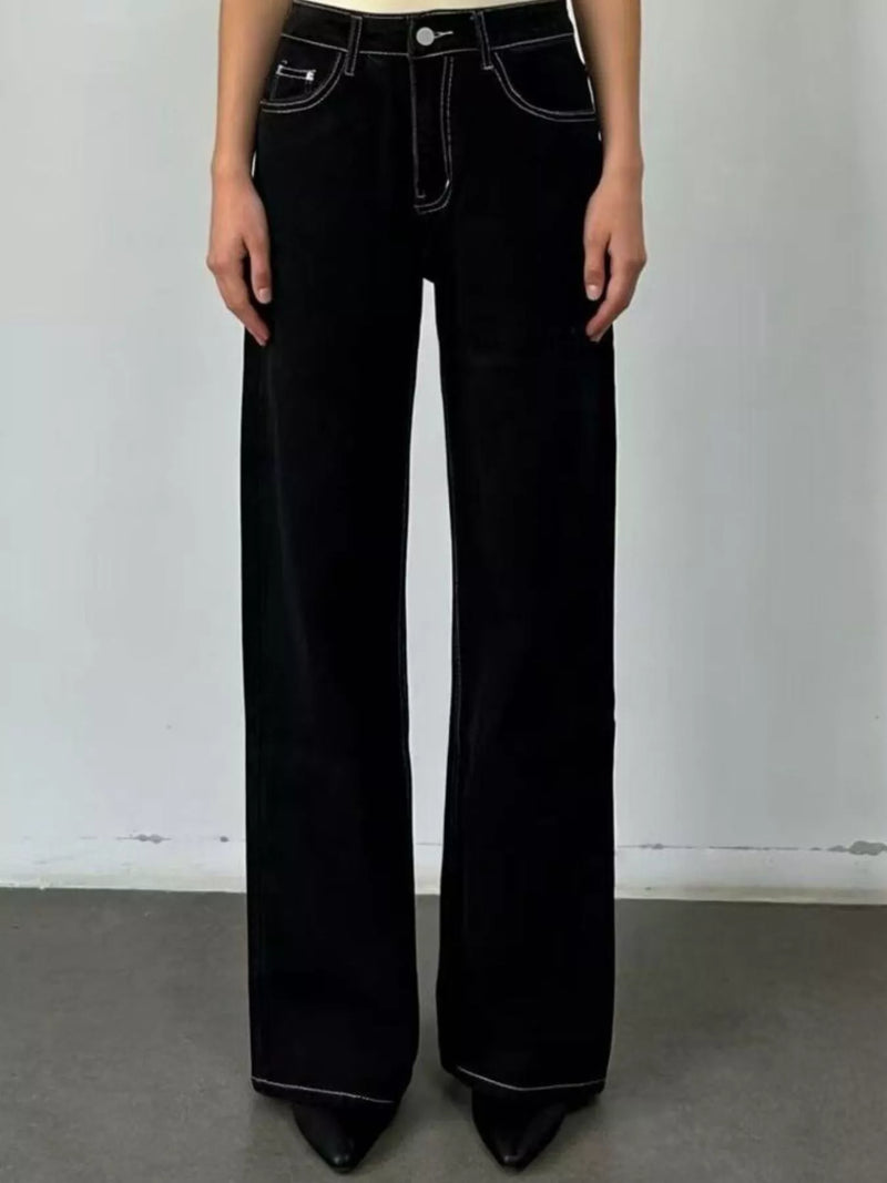 Person wearing black flared jeans against a plain background