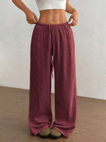Person wearing maroon wide-leg pants with a white top against a neutral background