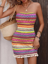 Woman wearing a colorful strapless dress with a straw bag.