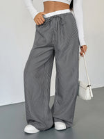 Person wearing gray striped wide-leg pants with a white background