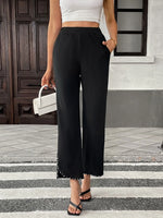 Person wearing black wide-leg pants and a white top on a city street.