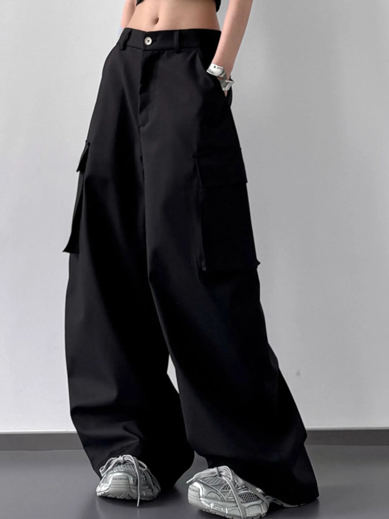 Person wearing black wide-leg cargo pants with a plain background