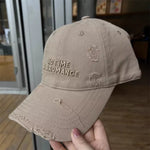 Beige cap with 'No Time For Romance' text held by a hand indoors.