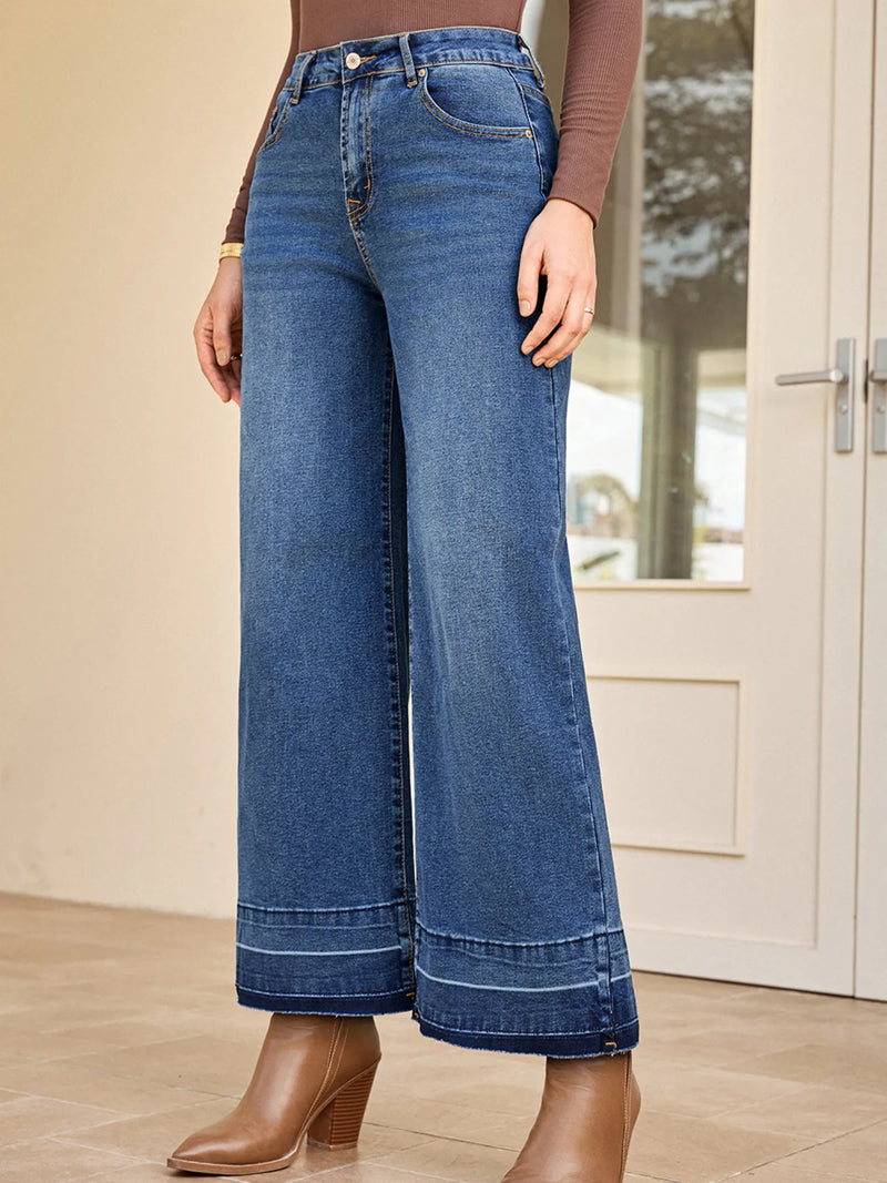 Person wearing blue wide-leg jeans indoors with a neutral background