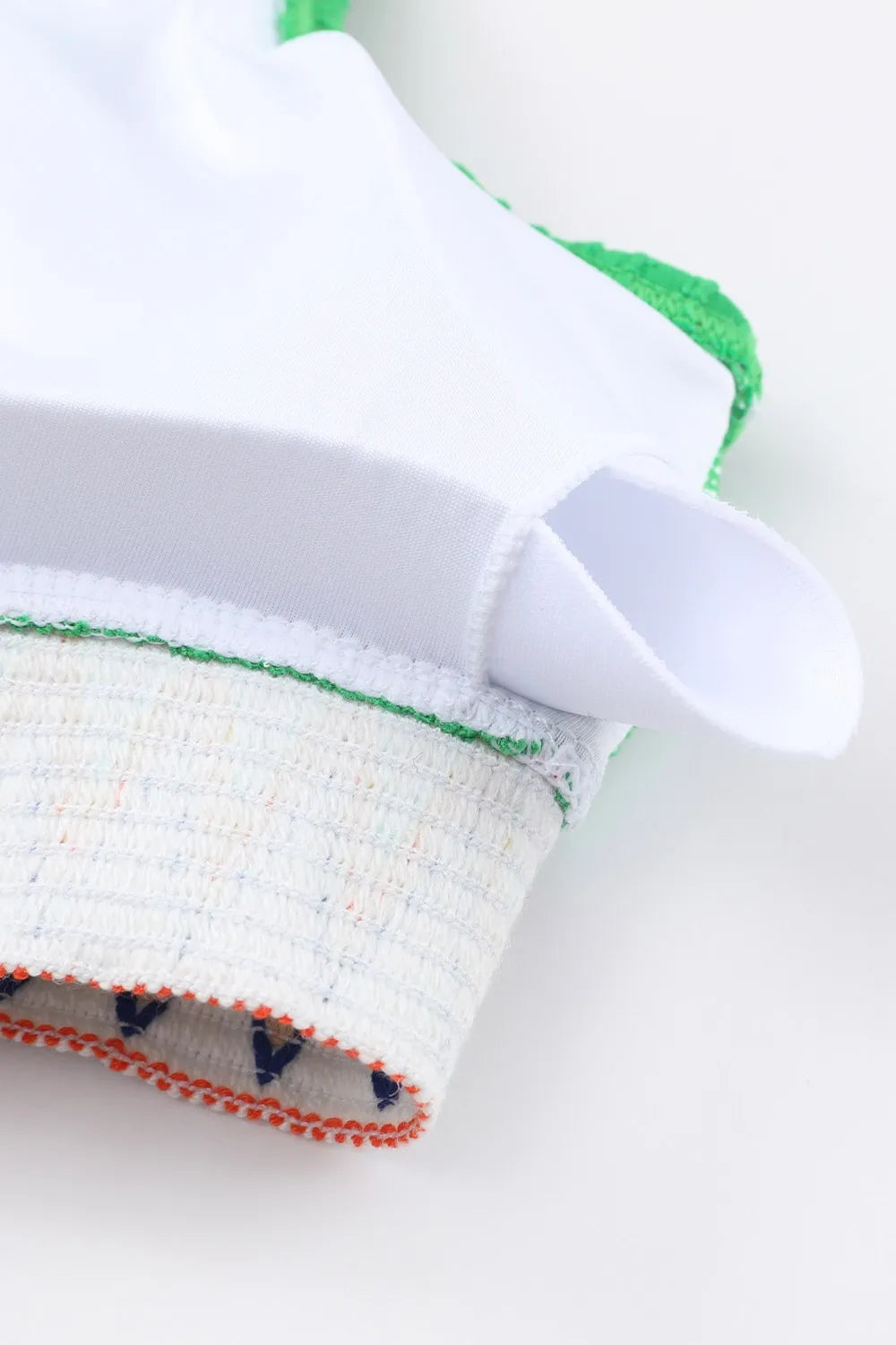 Close-up of a white glove with green and red accents on a white background