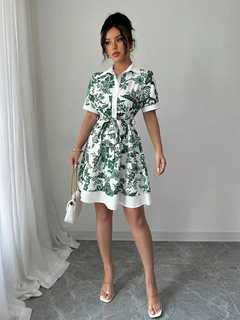 Woman wearing a green and white floral dress in a room with gray flooring and white curtains.