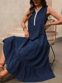 Woman wearing a navy blue dress with white trim sitting on a chair.