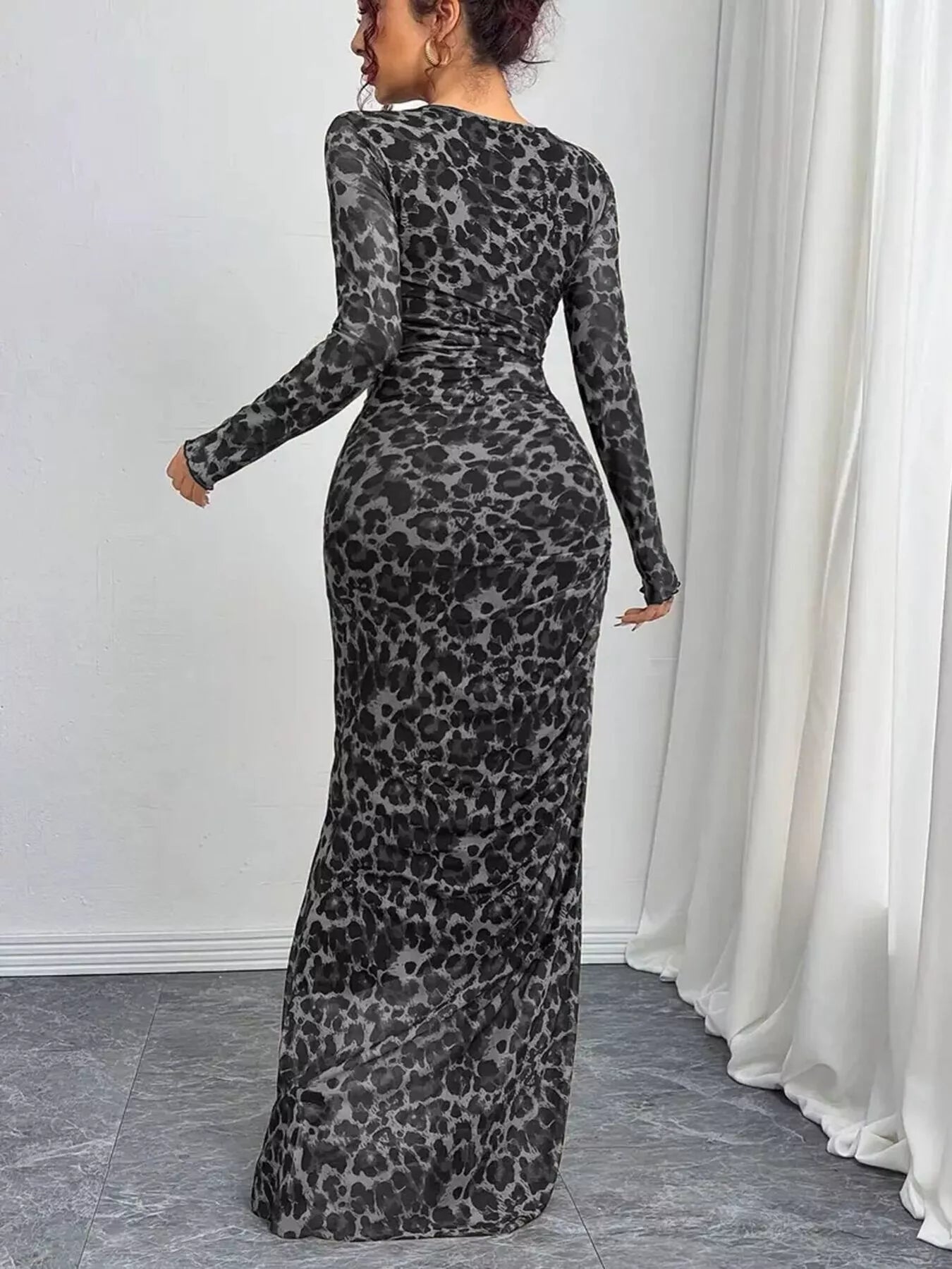 Woman wearing a leopard print long-sleeve dress against a white curtain background