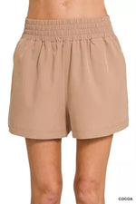 Beige shorts worn by a person on a white background