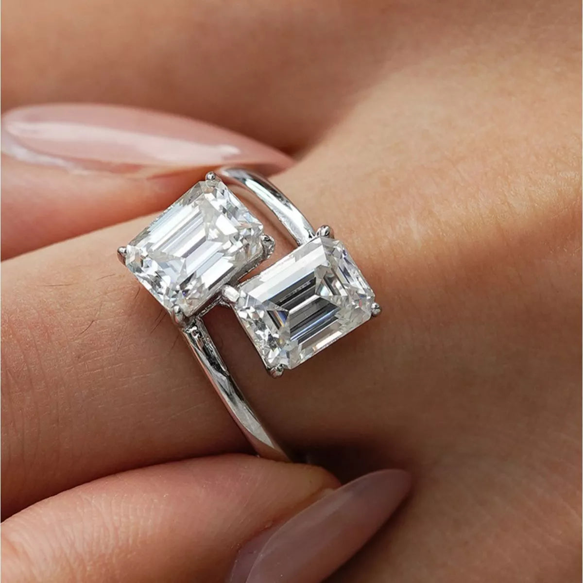 Silver ring with emerald-cut diamonds on a hand