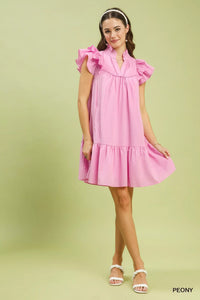 Young girl wearing a pink dress with ruffled sleeves on a light green background