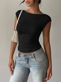 Person wearing a black top and light blue jeans with a beige bag on a neutral background