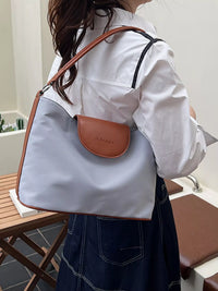 Person wearing a light blue handbag with brown accents