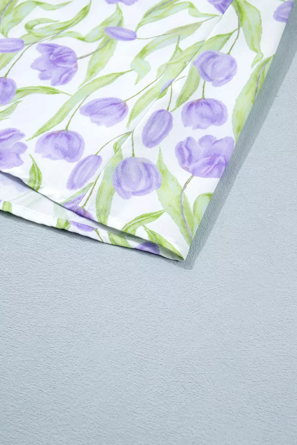 Floral-patterned paper with purple tulips and green leaves on a gray background