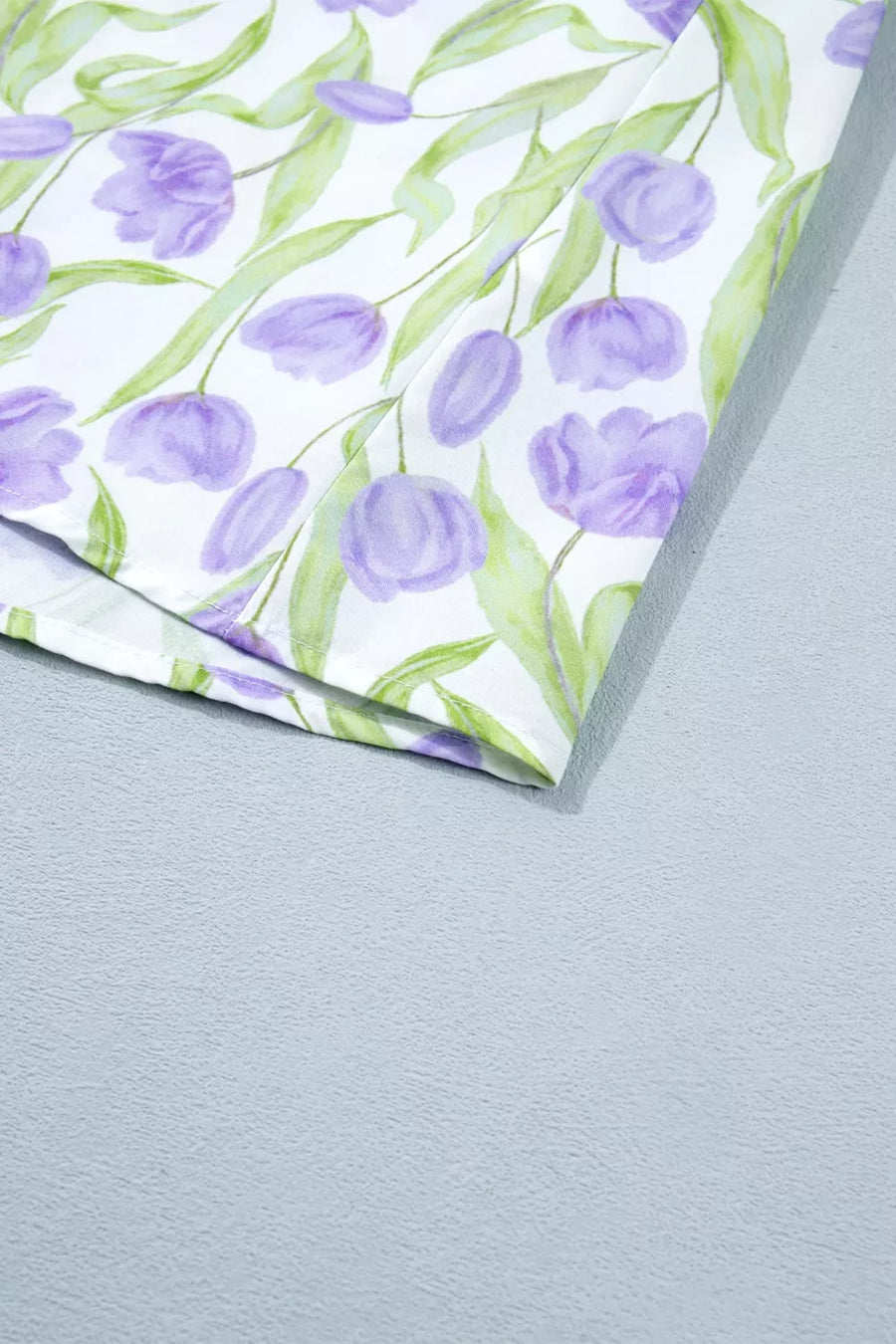 Floral-patterned paper with purple tulips and green leaves on a gray background