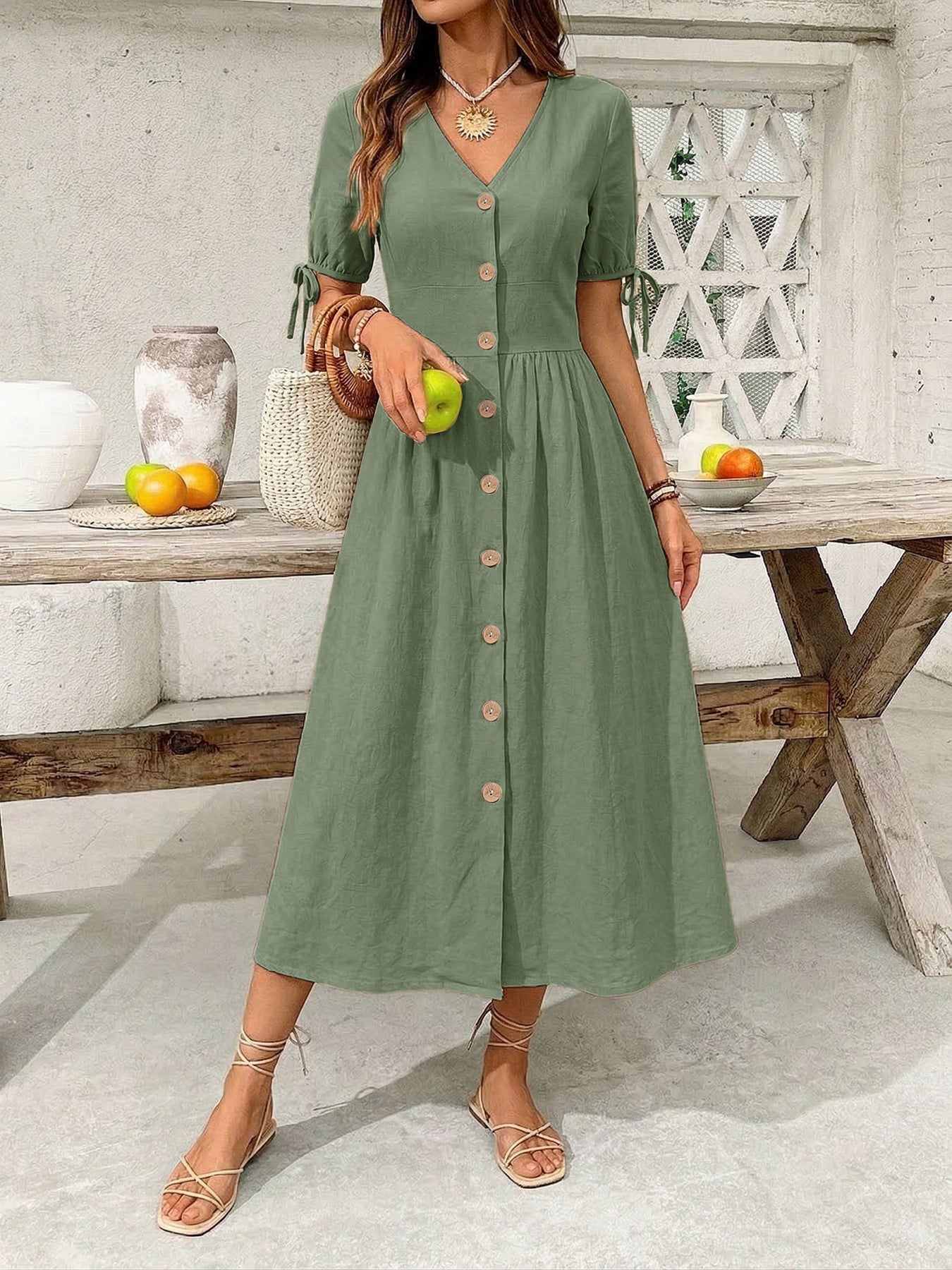 Woman in a green dress holding an apple in a casual setting.