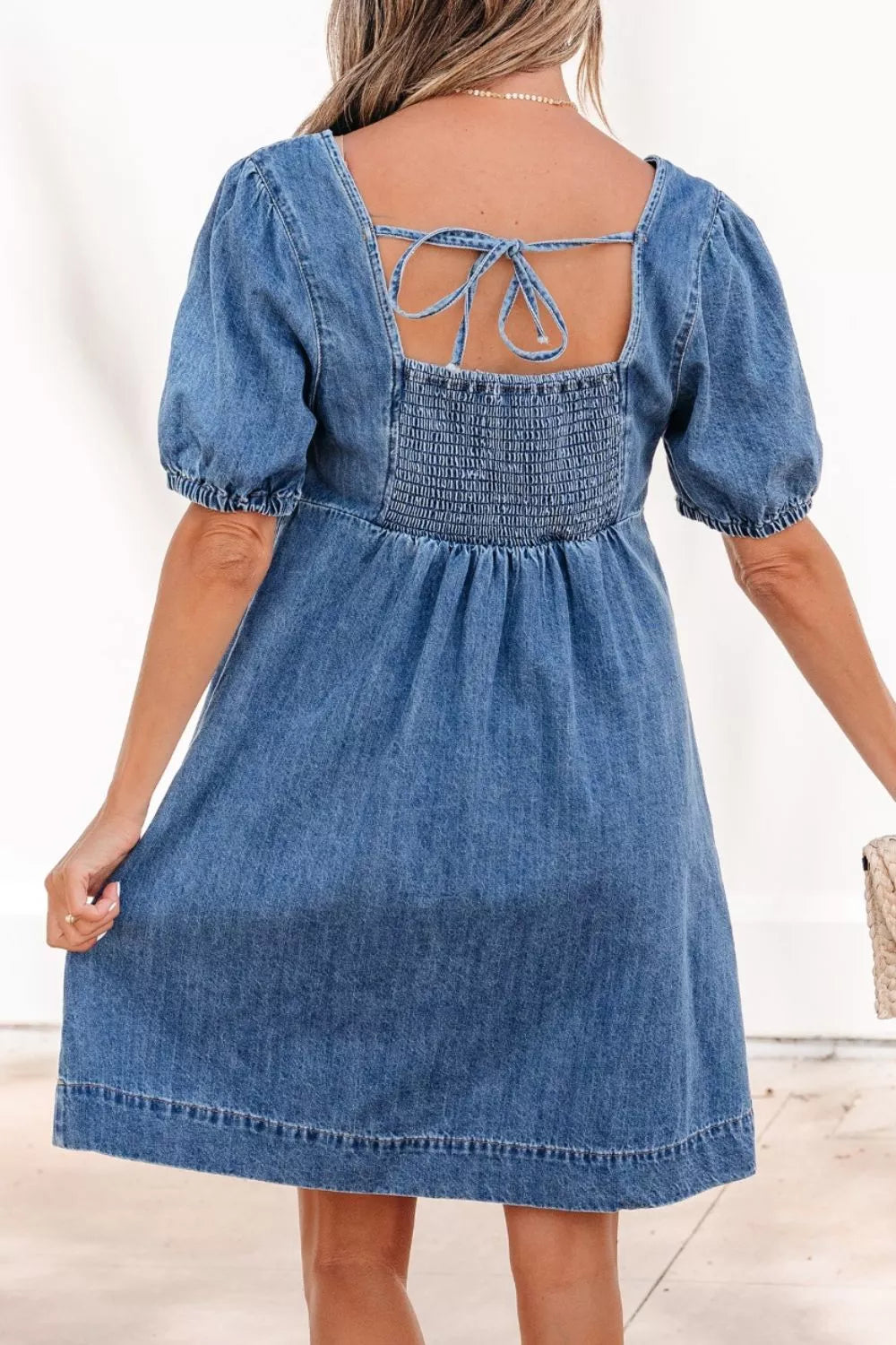 Blue denim dress with puff sleeves on a plain background