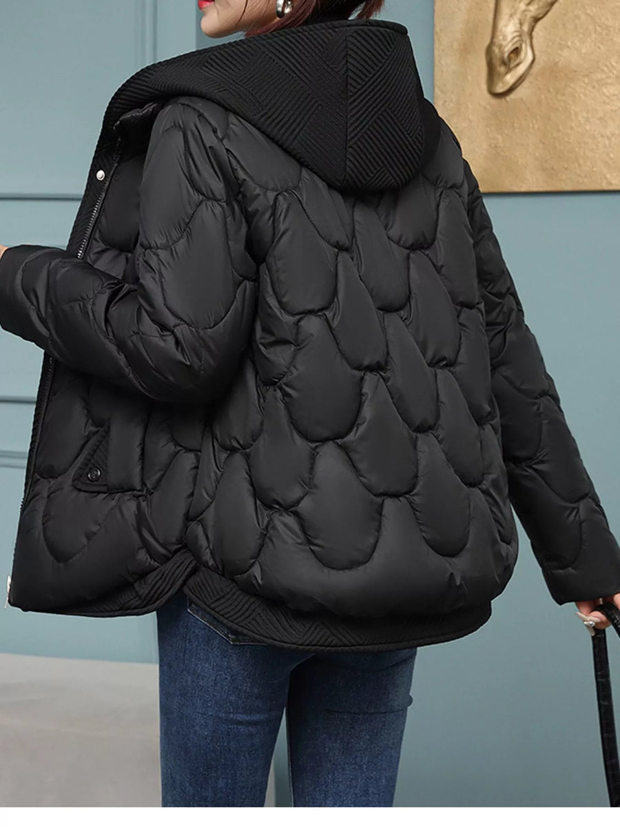 A woman wearing a black quilted puffer jacket with a hood, shown from the back. The jacket features a distinctive scalloped quilted pattern on the back and ribbed knit trim on the hood, cuffs, and hem.