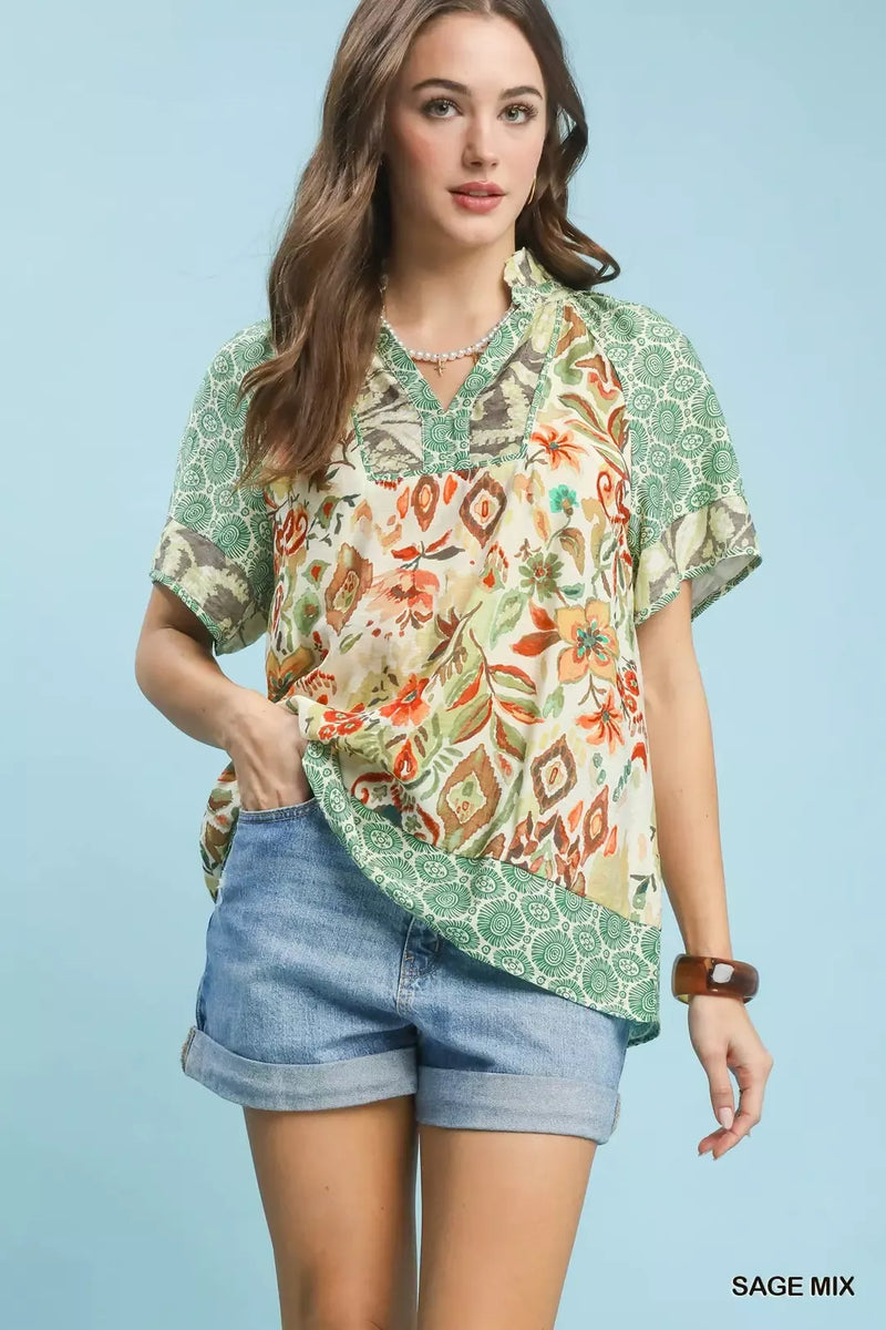 Woman wearing a patterned blouse and denim shorts on a light blue background