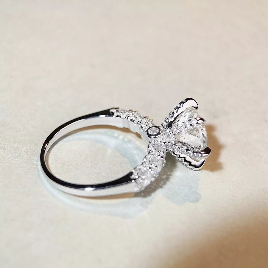Silver bow-shaped ring with a diamond on a beige background