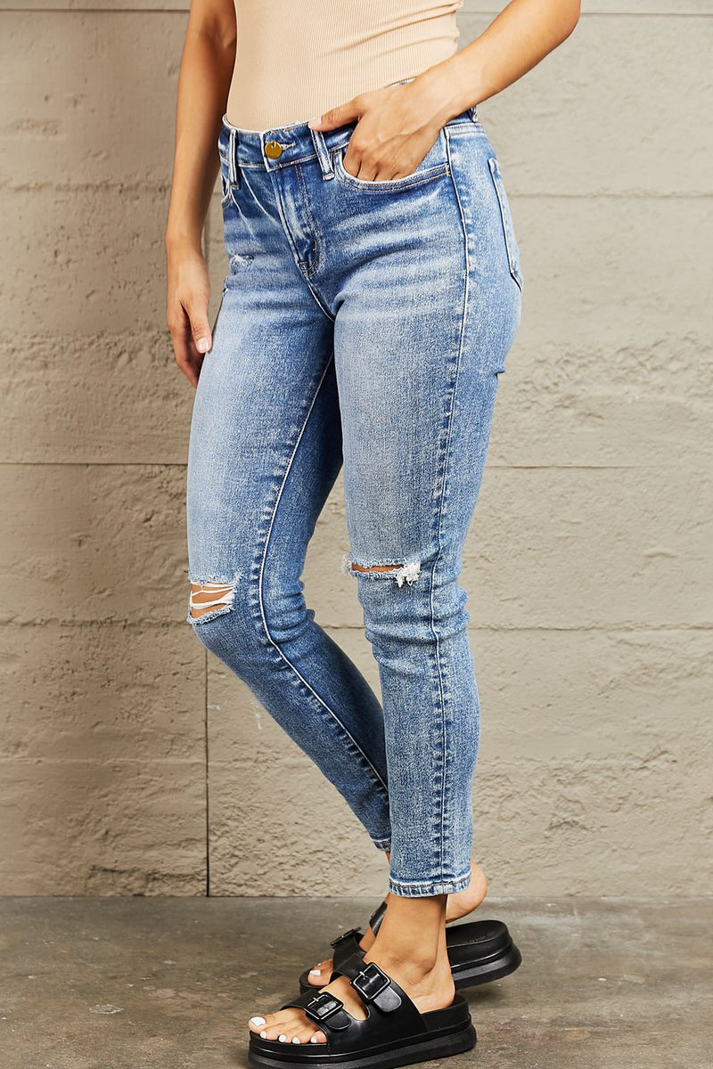 Person wearing blue ripped jeans against a gray wall