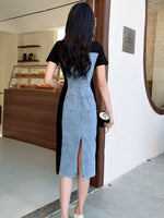 Woman wearing a black and denim dress standing in front of a store entrance.