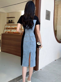 Woman wearing a black and denim dress standing in front of a store entrance.