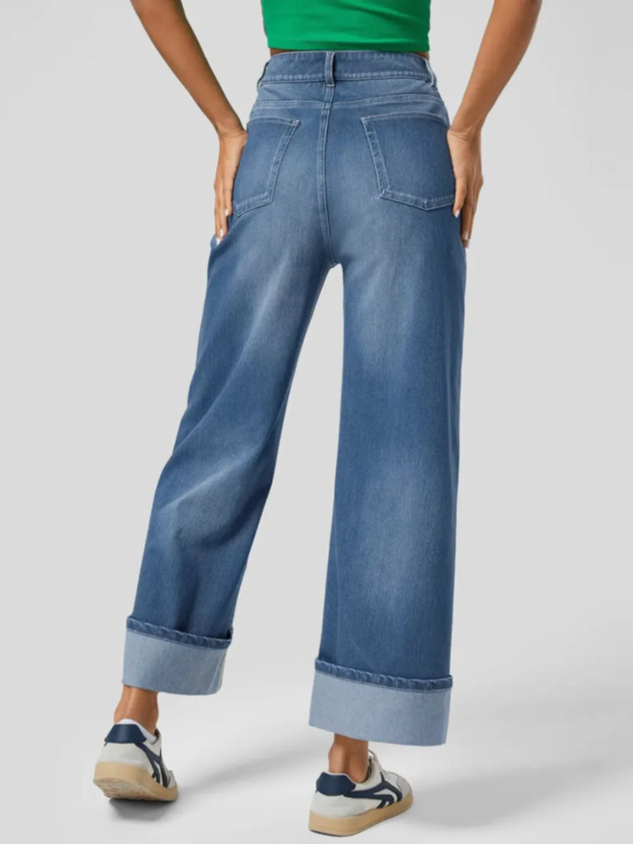 Person wearing blue jeans on a plain background