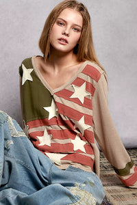 Woman wearing a sweater with an American flag pattern against a neutral background
