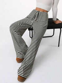 Black and white striped pants worn by a person sitting on a chair.