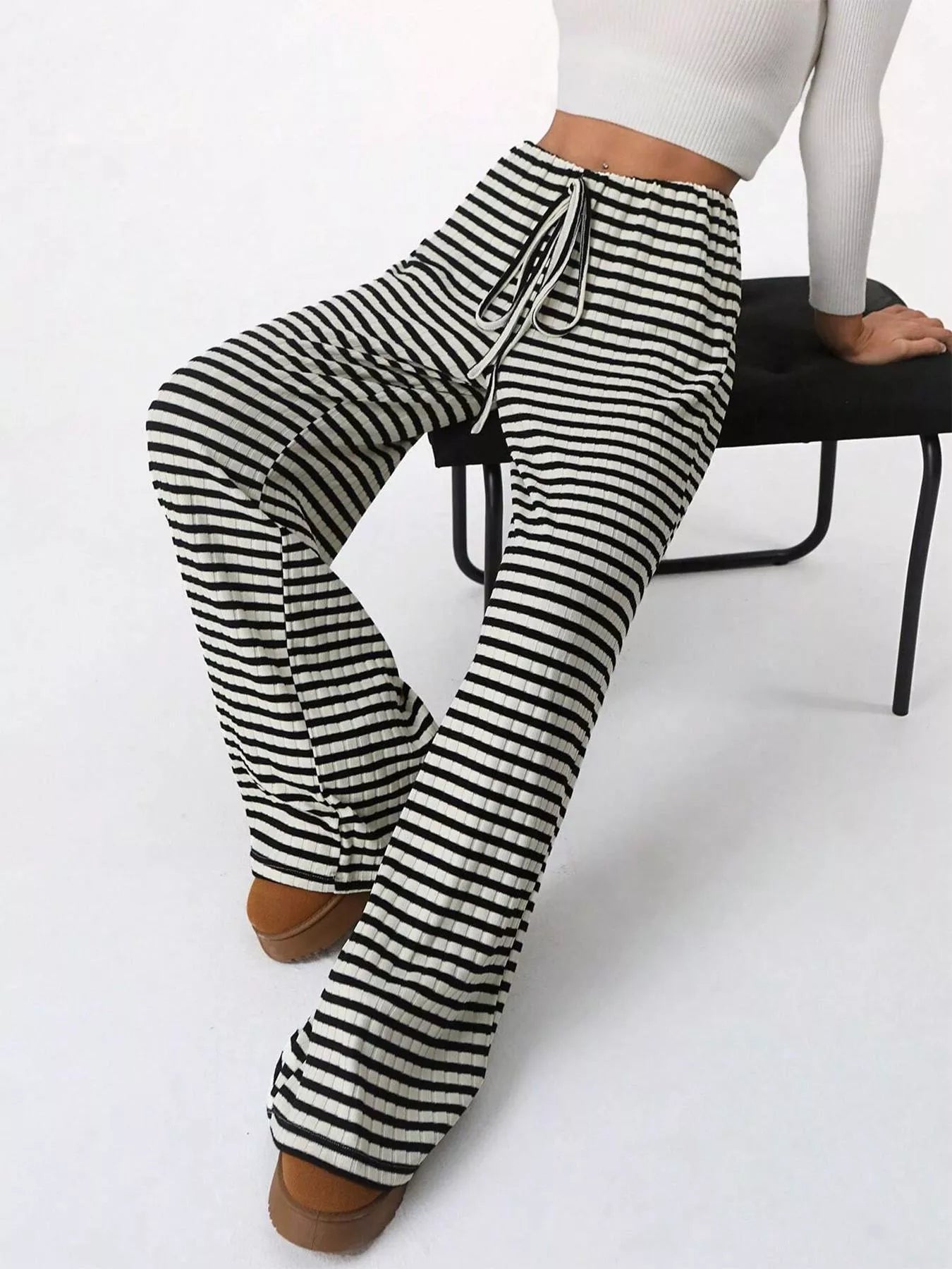 Black and white striped pants worn by a person sitting on a chair.