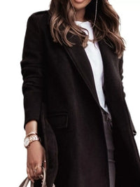 Person wearing a black coat over a white shirt on a plain background