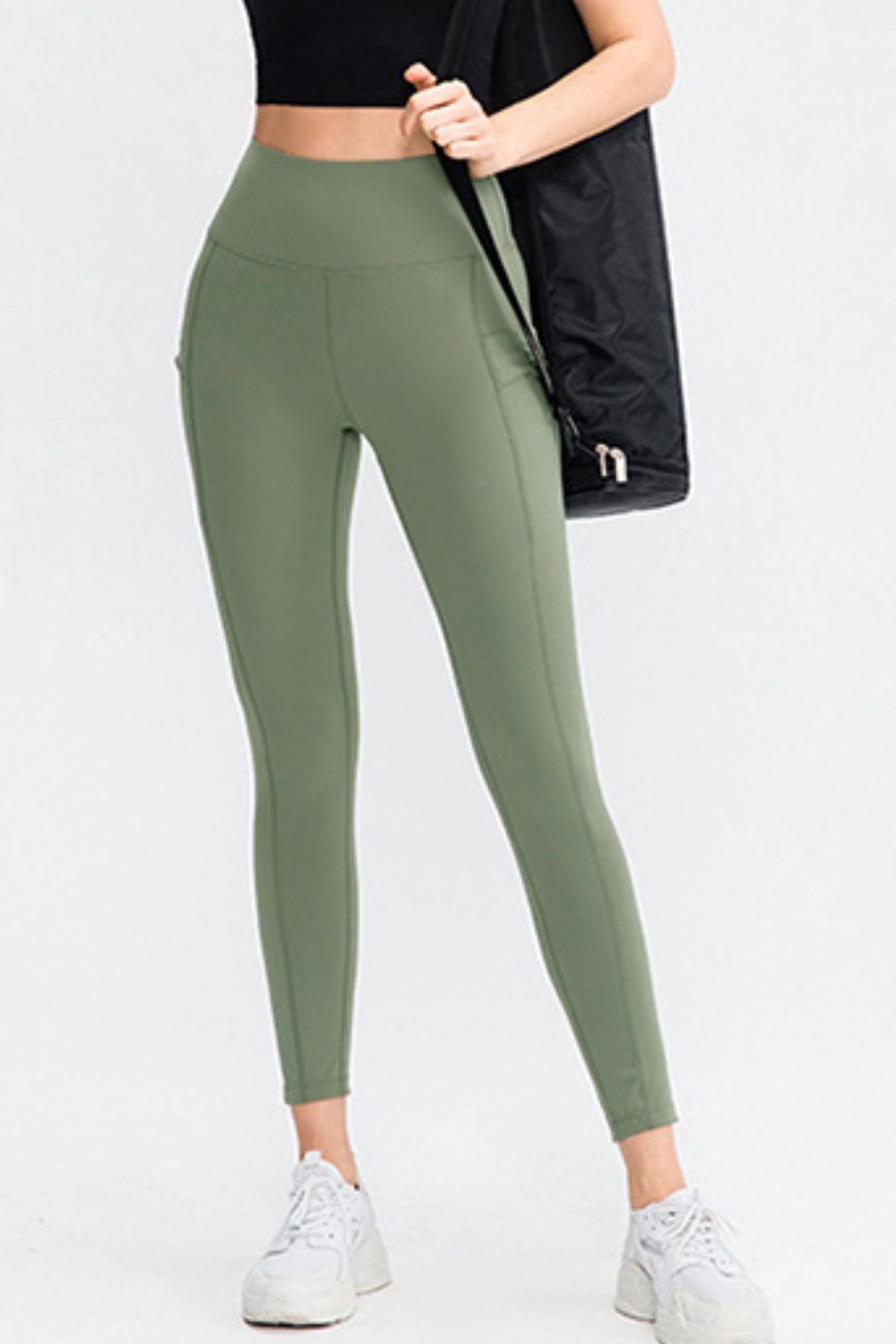 Person wearing green leggings with a black jacket on a white background