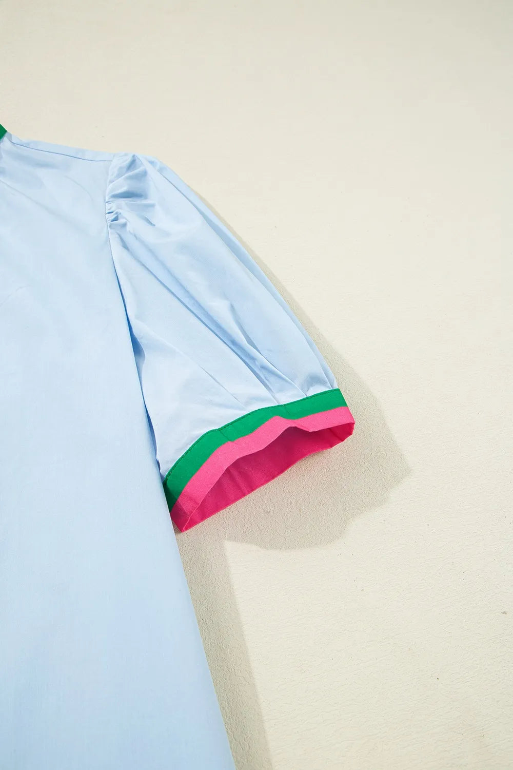 Light blue garment with colorful trim on a beige background