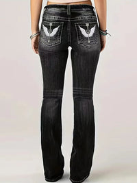 Black jeans with eagle designs on the pockets against a light background