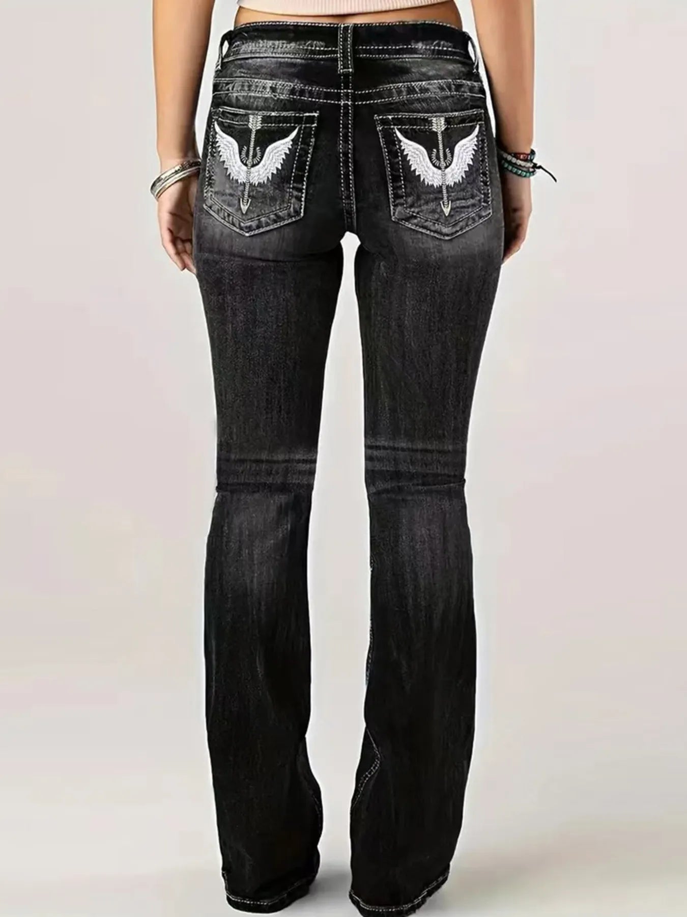 Black jeans with eagle designs on the pockets against a light background